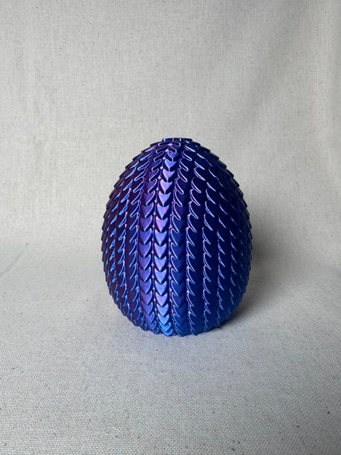 3D printed purple and blue articulated dragon emerging from a scale egg.