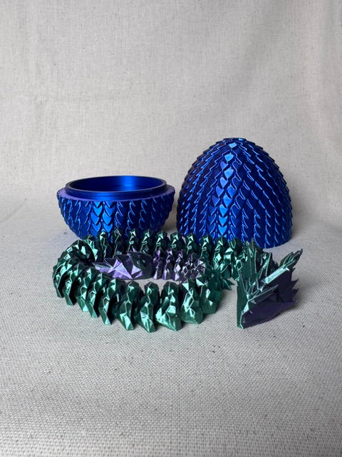 3D printed purple and blue articulated dragon emerging from a scale egg.